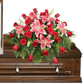 Red roses and pink lilies arranged on a wooden casket
