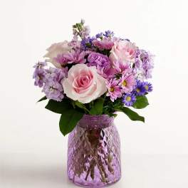 Pink and lavender bouquet in a purple glass vase