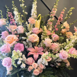 Tall pastel floral arrangement in a white vase with roses, lilies, and snapdragons