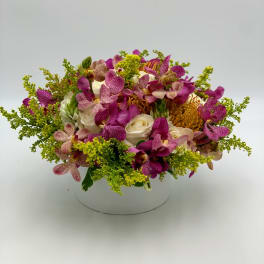 Round bouquet of pink orchids and white roses in a white container