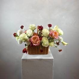 Basket arrangement with roses, calla lilies, and white blooms