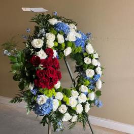 Large standing floral wreath with red, white, and blue flowers on an easel