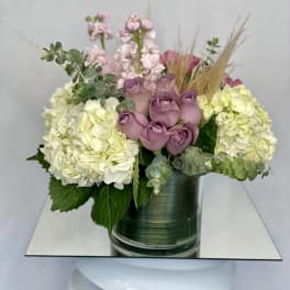 Lavender roses and pale hydrangeas in a green glass vase