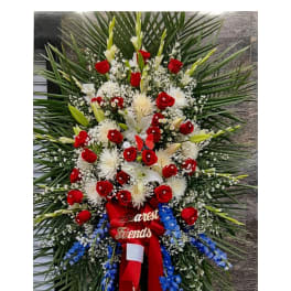 Large standing floral spray with red roses, white lilies, and blue flowers