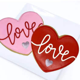 Two heart-shaped cookies with the word love on a white card