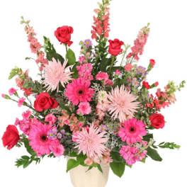 Pink and red mixed flower arrangement in a cream vase
