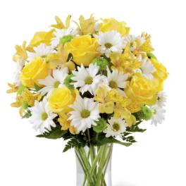 Yellow roses and white daisies in a clear glass vase
