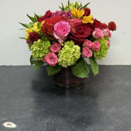 Mixed bouquet of pink and red roses with green hydrangeas in a glass vase