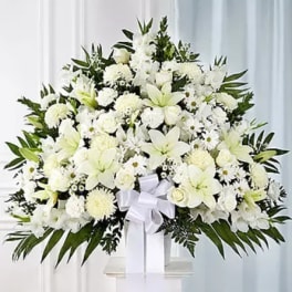 Large white funeral spray with lilies and roses on a stand