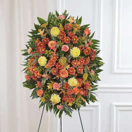 Standing floral wreath with orange, yellow, and pink blooms on an easel