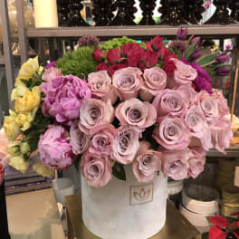 Mixed bouquet of pink and purple roses in a white hatbox