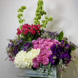 Large mixed bouquet in a rectangular vase with pink, purple, white, and green flowers
