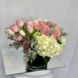 Pink tulips and roses with pale hydrangea in a glass vase