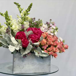 Mixed bouquet of pink and peach roses in a rectangular metal container
