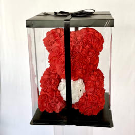 Red teddy bear made of roses in a clear gift box with a black ribbon