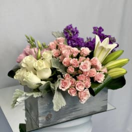 Bouquet of pink and white roses with purple flowers in a wooden box