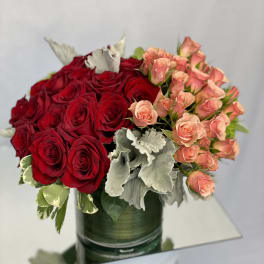 Red and peach roses arranged in a green glass vase