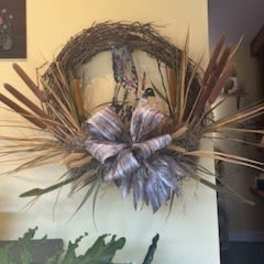Decorative wreath with a large striped bow and dried grasses