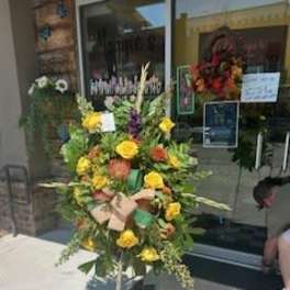 Tall floral standing spray with yellow and orange blooms on an easel