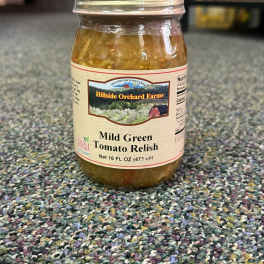 Jar of mild green tomato relish on a carpeted floor