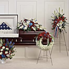 Patriotic funeral floral set with red, white, and blue arrangements around a casket