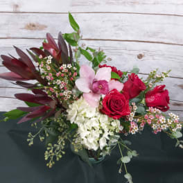 Bouquet of red roses, pink orchid, and white hydrangea in a glass vase