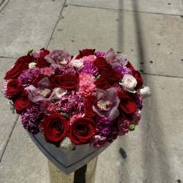 Heart-shaped bouquet of red roses, pink carnations, and orchids