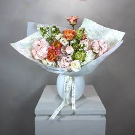 Bouquet of pastel roses and hydrangeas in white wrapping, tied with ribbon