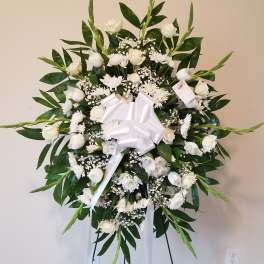 White funeral wreath on an easel with a satin bow
