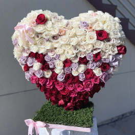 Heart-shaped rose arrangement in white, pink, and red with a pink ribbon