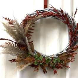 Decorative wreath with dried grasses and red foliage on a silver ring