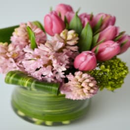 Pink tulips and pale pink flowers in a green glass vase