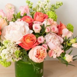 Pink and coral roses arranged in a green glass vase