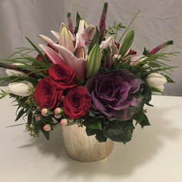 Mixed bouquet of red roses, pink lilies, and purple ornamental cabbage in a vase