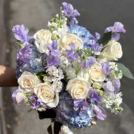 Bouquet of cream roses, blue hydrangeas, and lavender flowers