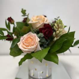 Bouquet of peach and burgundy roses in a clear vase