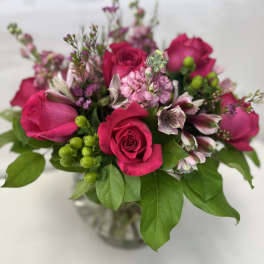 Pink roses and mixed blooms arranged in a glass vase