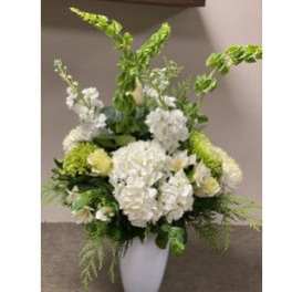White floral arrangement in a tall vase with green accents