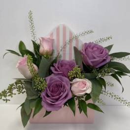 Pink and purple roses arranged in a pastel gift box