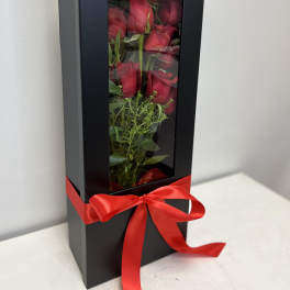 Boxed arrangement of red roses with a red ribbon