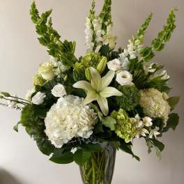 White and green floral arrangement in a clear glass vase