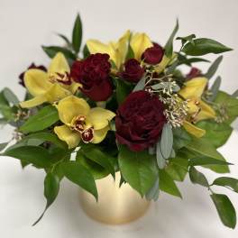 Bouquet of red roses and yellow orchids in a gold vase
