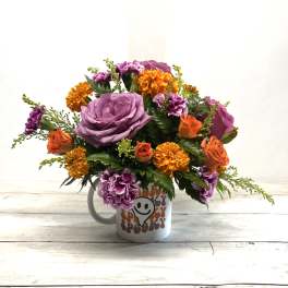 Bouquet of purple and orange flowers in a white mug