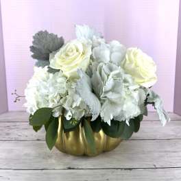 White roses and hydrangeas in a gold pumpkin vase