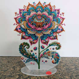 Colorful jeweled floral ornament shaped like a stylized flower on a clear acrylic stand.