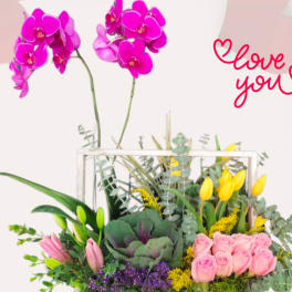 Mixed floral arrangement in a white wooden box with pink orchids and roses