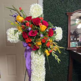 Standing floral cross with red, yellow, and white flowers on an easel