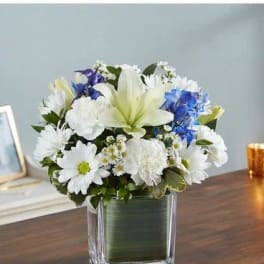 White and blue flower arrangement in a square glass vase