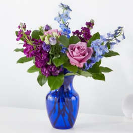 Pink rose bouquet with blue and purple flowers in a cobalt vase
