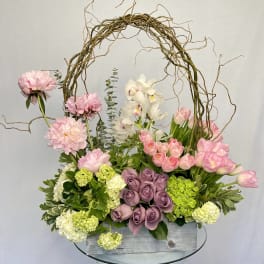 Pink and white floral arrangement in a wooden box with a twig arch